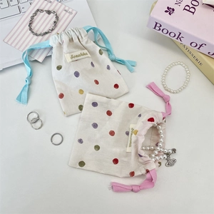 Gros plan de petits sacs en coton à cordon avec pois colorés et étiquettes tissées