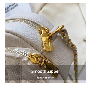 Detail of smooth gold zippers and white lychee leather on this crossbody bag