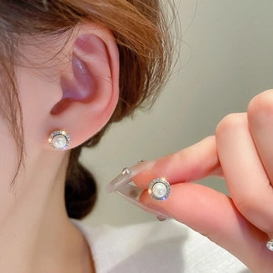 Elegant silver stud earrings with central pearl and sparkling zircon halo on model
