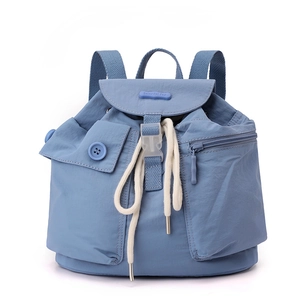 Detailed view of light blue nylon backpack featuring a buckled flap and front pockets
