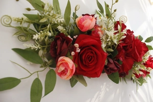 Detail shot of red and pink artificial roses with green foliage and white accents