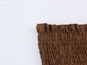 Detail of brown smocked fabric with textured elastic finish and wavy stitched edges
