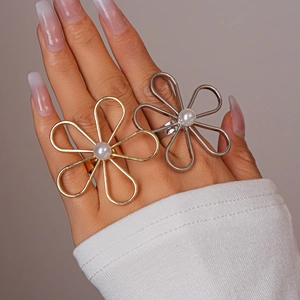 Detail of large hollow floral ring with pearl center in gold and silver finishes