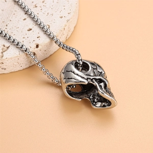 Macro shot of silver stainless steel skull necklace on stone with round bead chain