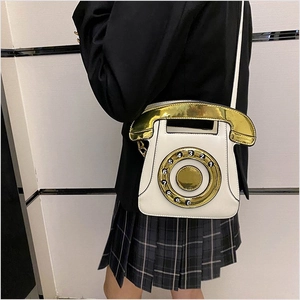 Close-up of white retro telephone shaped crossbody bag with gold dial and handle details