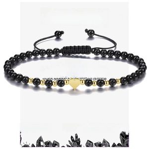 Detailed macro view of black hematite beads and a gold heart charm on an adjustable band