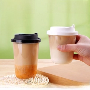 Close-up of a hand holding a thick disposable plastic coffee cup with a U-shaped base