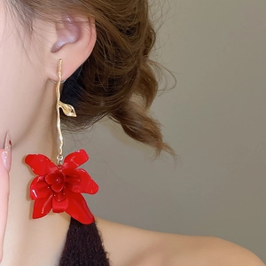 Detail of red floral pendant earrings with gold wavy branch on a model close-up