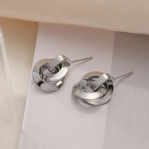 Minimalist geometric circle drop earrings in silver finish on soft fabric background