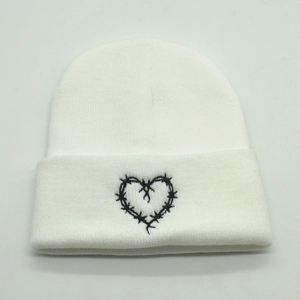 White knit beanie with black Bichota thorn heart embroidery on a minimalist background