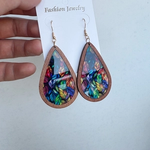 Close-up of wooden teardrop earrings with colorful leaf patterns on a display card