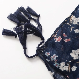 Detailed view of dark blue cotton scarf with floral print and handmade tassels