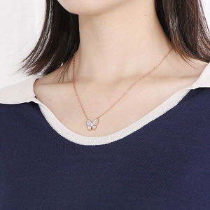 Detail of rose gold butterfly pendant with white mother-of-pearl and crystal on neck