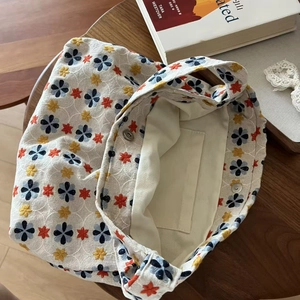 Detail of floral embroidery on linen tote bag showing magnetic buckle and inner pocket