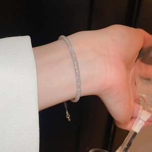 Bracelet en maille tissée argentée avec zircons porté par un mannequin élégant