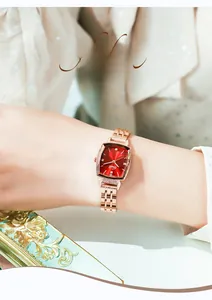 Detail of rose gold tonneau watch with red sunray dial and diamond accents on wrist