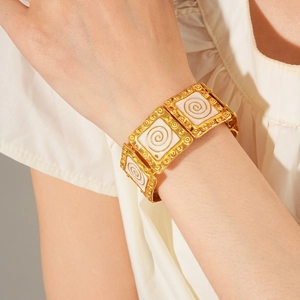 Detailed view of vintage gold enamel square link bracelet with spiral texture on wrist