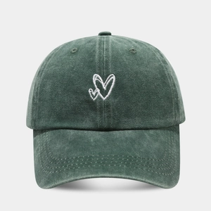Detailed embroidery of white double hearts on a washed green cotton baseball cap