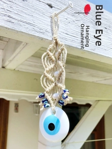 Detail of handmade woven boho Evil Eye wall hanging with blue beads on white cotton rope