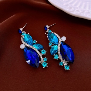 Macro view of blue teardrop gemstones and silver diamond studs on silk fabric