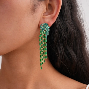 Model wearing gold tassel earrings with blue and green crystals in a stylish side view