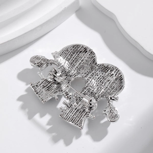 Back view of silver metal snowman brooch showing safety pin clasp and textured finish