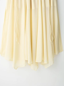 Detail of light yellow skirt featuring irregular hem and drawstring fabric texture