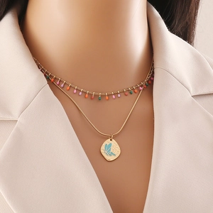 Collier double rang doré avec perles colorées et pendentif papillon bleu sur un mannequin