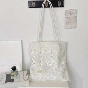 Détail du sac cabas en dentelle blanche à fleurs suspendu dans un décor élégant