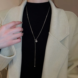 Silver adjustable necklace with hollow spherical pendant worn on a black sweater