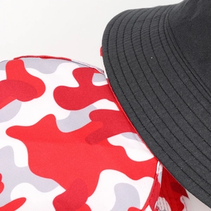 Détail du chapeau bob réversible montrant la couture noire et l'imprimé camouflage rouge