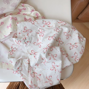 Détail du sac bandoulière en coton avec motifs floraux rouges et nœuds roses