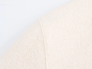 Close-up of white boucle wool fabric showing plush texture and premium stitching