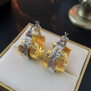 Two-tone gold and silver metal hoop earrings with textured hammered finish on cushion