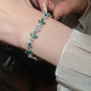Close-up of elegant silver bracelet with marquise-cut green zircon and leaf design
