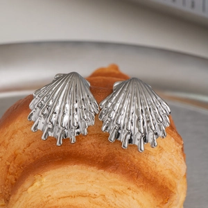 Macro detail of silver shell-shaped earrings featuring a radiant metallic texture