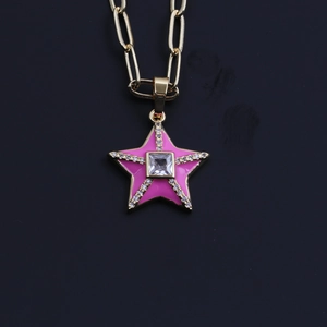 Macro view of gold chain link with pink zircon star pendant and sparkling stone detail