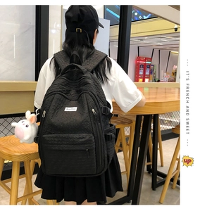 Détail du sac à dos noir gaufré avec pendentif lapin et compartiments zippés