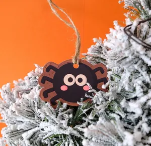 Close-up of cute cartoon spider Halloween tag with twine on frosted pine needles