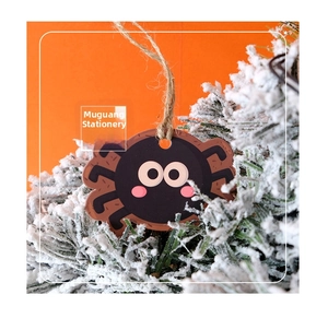 Close-up of cute cartoon spider Halloween tag with twine on frosted pine needles