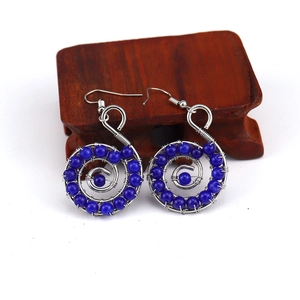 Close-up of handmade blue bead spiral earrings with silver wire wrap on wooden stand