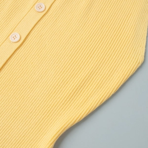 Vue macro de la texture en maille côtelée jaune pâle et boutons crème soyeux