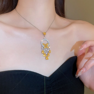Detailed view of a silver tassel necklace with yellow crystal butterflies on model neck