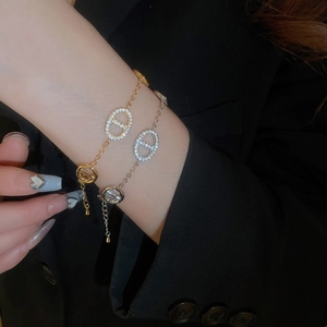 Close-up of gold and silver plated zircon oval link bracelets on black suit sleeve