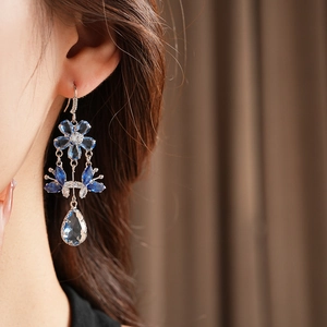 Close-up of elegant flower and waterdrop tassel earrings with blue and clear zircons