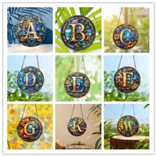 Detail view of 9 suncatcher charms with golden initials and floral stained glass patterns