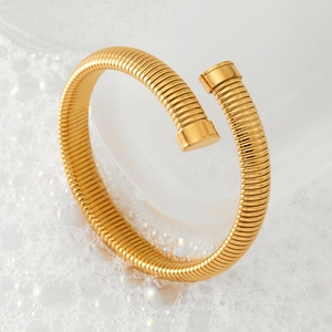 Minimalist golden spring open bangle with spiral texture in a clean water drop aesthetic