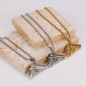 Three men's stainless steel pistol necklaces in silver, gold, and gun black on stone