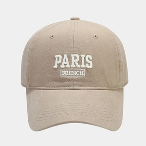 Detailed close-up of white PARIS embroidery on khaki cotton baseball cap fabric
