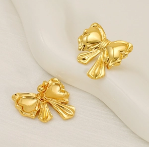 Detailed macro view of gold-finished butterfly bow earrings with four-heart wing design